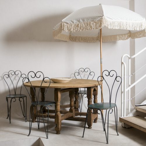 Sombrilla de color blanco con estampado verde con flecos y poste de madera