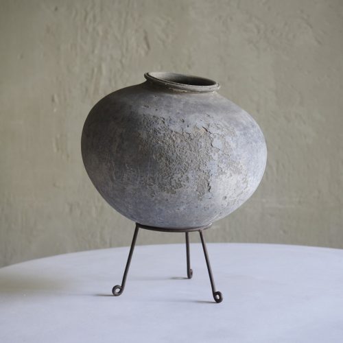 Vasija de barro antigua sobre soporte de hierro